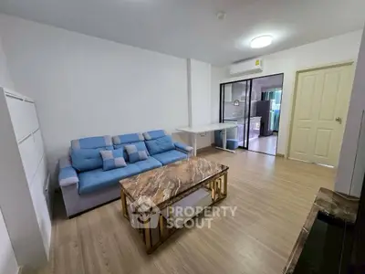 Modern living room with stylish furniture and open layout, featuring a blue sofa and marble coffee table.