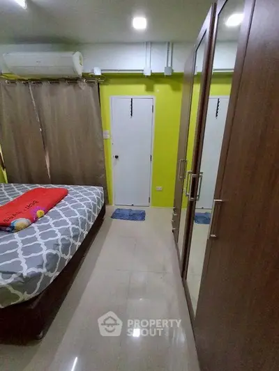 Cozy bedroom with mirrored wardrobe and vibrant yellow accent wall