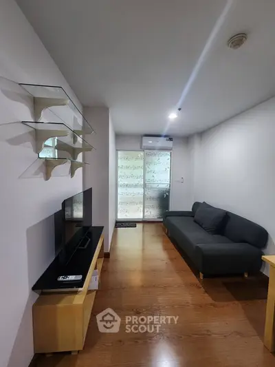 Modern living room with sleek furniture and wooden flooring, featuring a stylish sofa and wall-mounted shelves.