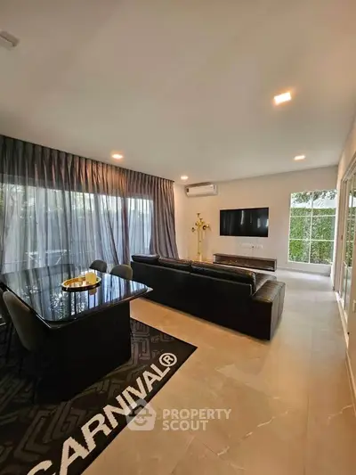 Modern living room with sleek black furniture and large windows offering natural light.