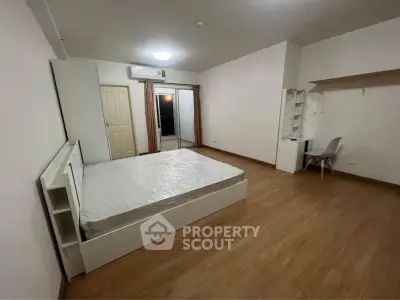 Spacious bedroom with wooden flooring and modern furniture in a cozy apartment.