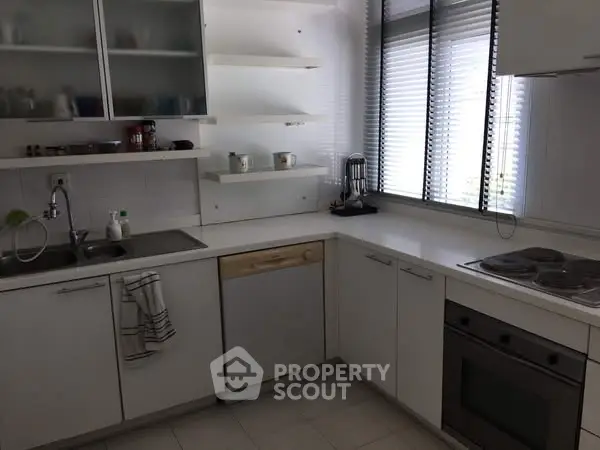 Modern kitchen with sleek white cabinets and built-in appliances.