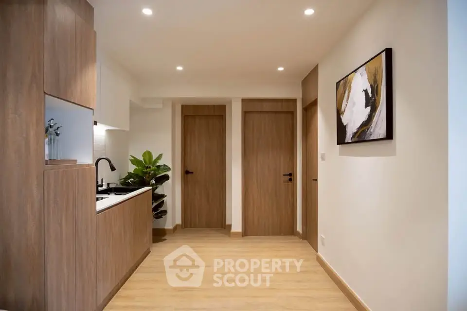 Modern interior hallway with wooden doors and sleek kitchen area, perfect for contemporary living.