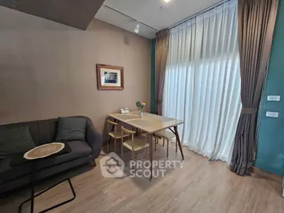 Cozy living room with elegant dining area, featuring stylish decor and natural light through large windows.