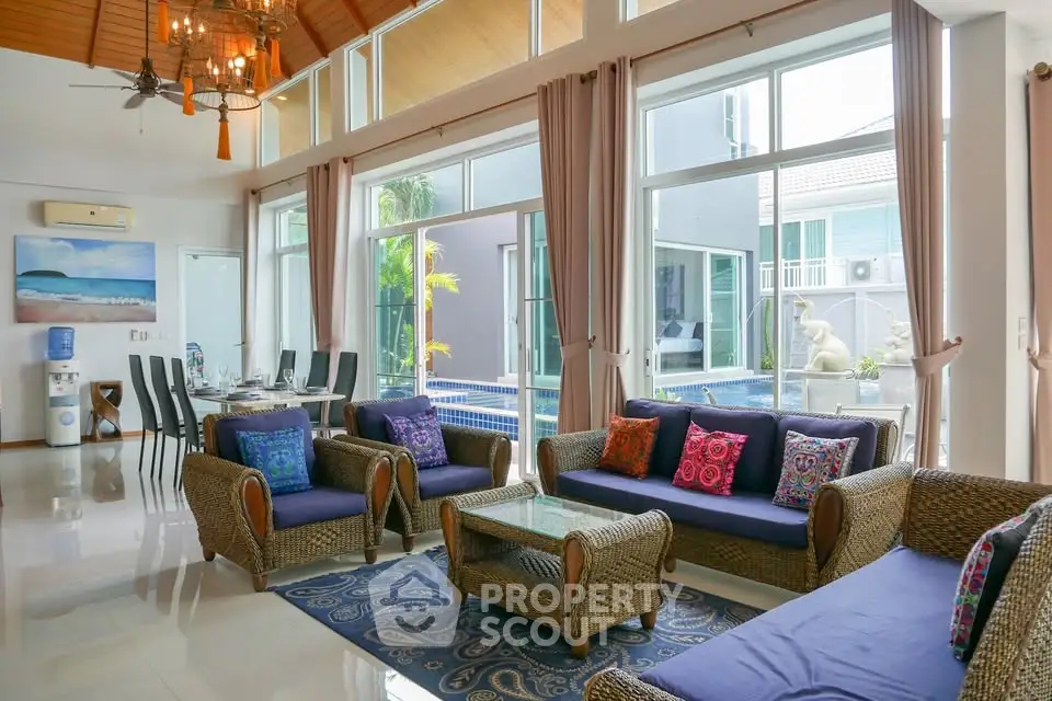 Luxurious living room with pool view, high ceilings, and elegant decor in a modern home.