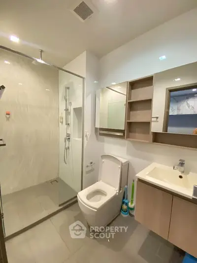 Modern bathroom with glass shower and sleek fixtures in contemporary apartment.