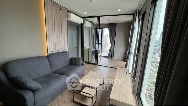 Modern living room with city view, featuring sleek furniture and floor-to-ceiling windows.