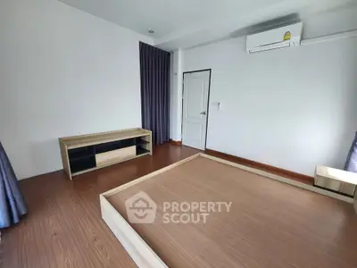 Spacious bedroom with wooden flooring and modern air conditioning unit.