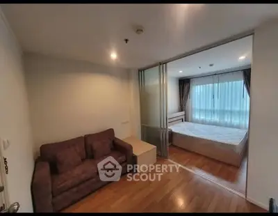 Cozy apartment with sliding glass doors separating living room and bedroom, featuring wooden floors.