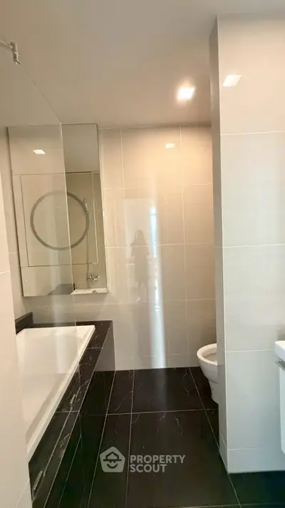 Modern bathroom with sleek design, featuring a bathtub and elegant tile work.