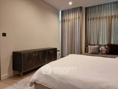 Elegant bedroom with a large comfortable bed, stylish dark wood dresser, and luxurious curtains enhancing the serene ambiance.