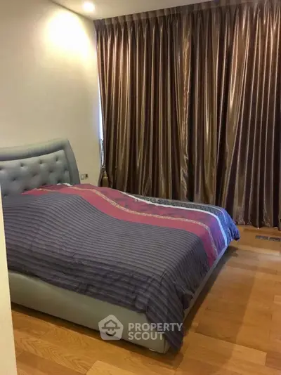 Cozy bedroom with elegant curtains and wooden flooring, featuring a stylish bed and ambient lighting.