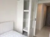 Modern bedroom with sleek white furniture and ample storage space.