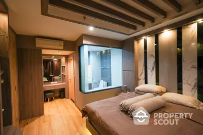 Luxurious bedroom with en-suite glass-walled bathroom, featuring warm wooden floors, elegant lighting, and modern furnishings, perfect for upscale urban living.