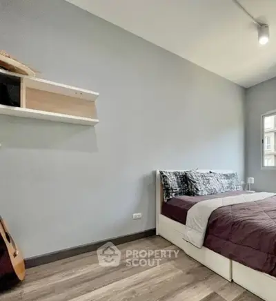 Cozy bedroom with modern decor and natural light, featuring a comfortable bed and stylish shelving.