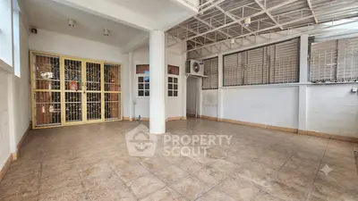 Spacious tiled patio with metal gate and air conditioning unit, ideal for outdoor gatherings.