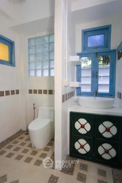 Charming bathroom with unique tile design and blue window frames