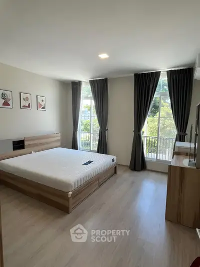 Spacious bedroom with large windows and modern decor, offering a serene view and ample natural light.