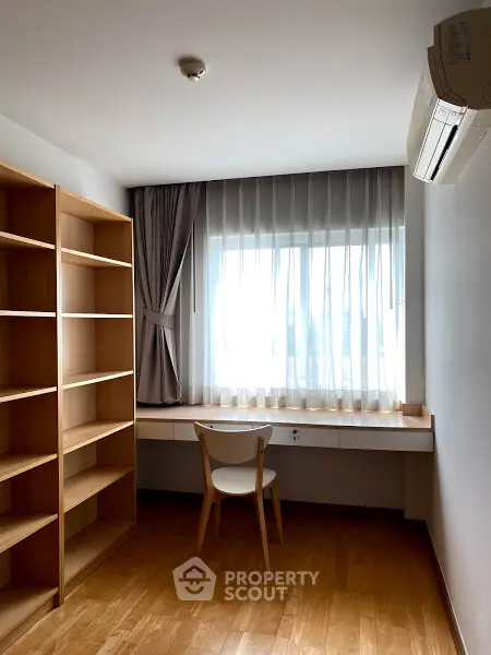 Bright study room with wooden shelves and desk, featuring large window and air conditioning.