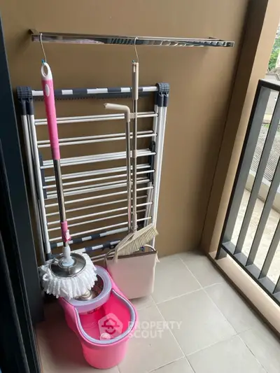 Compact balcony with cleaning tools and drying rack, ideal for urban living.