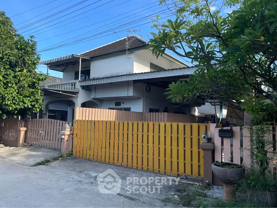 Charming suburban house with gated entrance and lush greenery