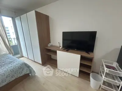 Modern bedroom with sleek furniture and large TV, featuring a cozy balcony view.