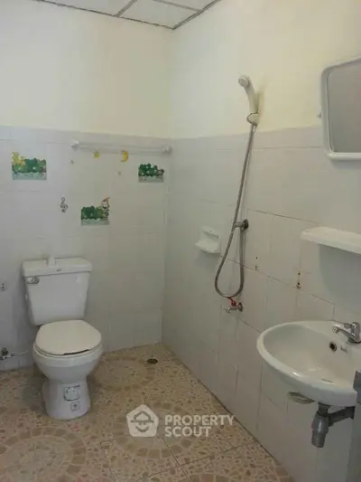 Simple bathroom with shower, toilet, and sink in a tiled setting.