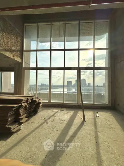 Spacious unfinished room with large windows offering stunning city skyline views.