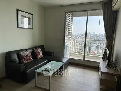 Modern living room with city view, featuring sleek furniture and large windows for natural light.