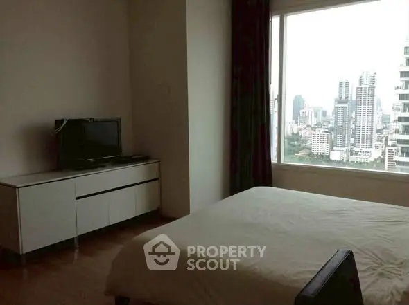 Modern bedroom with city view, featuring sleek furniture and large window.