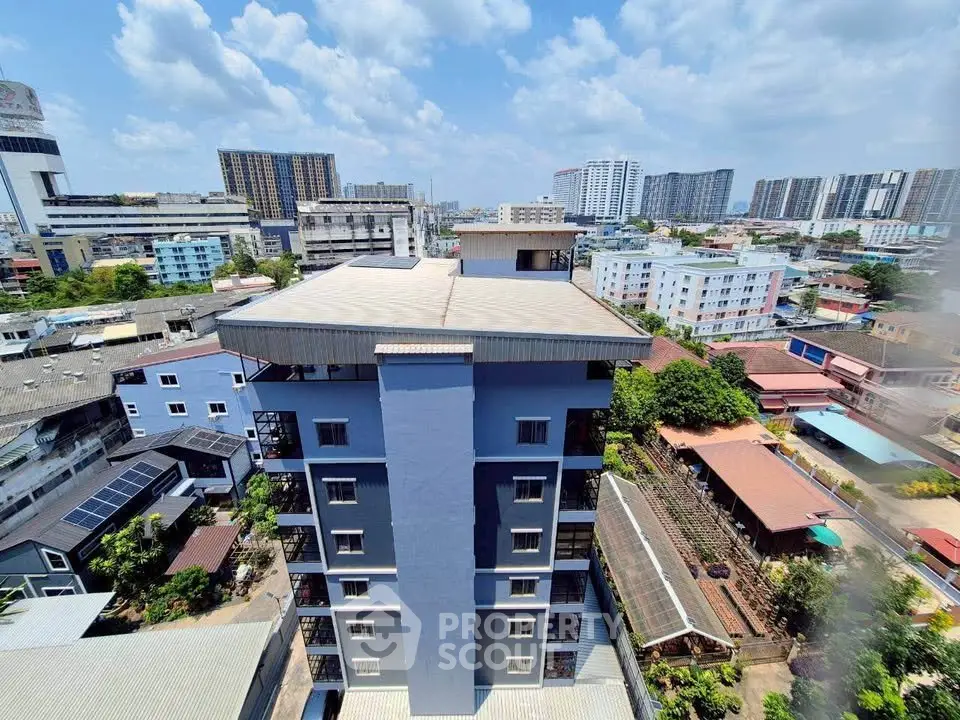 Stunning aerial view of urban residential building with cityscape backdrop and clear blue sky.