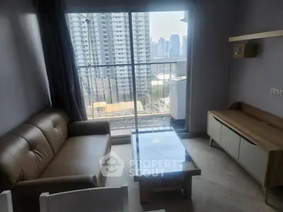 Modern living room with city view, featuring a sleek sofa and glass coffee table.
