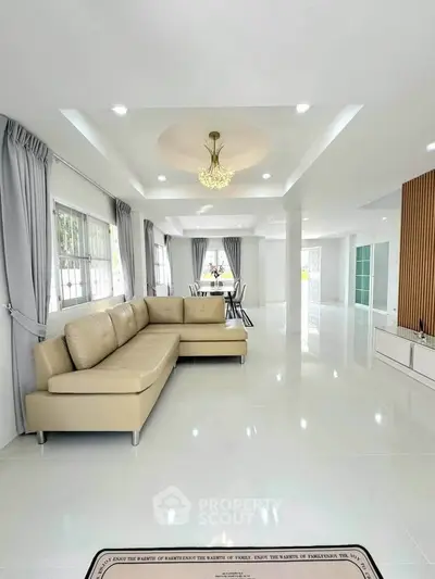 Spacious modern living room with elegant chandelier and beige sectional sofa.