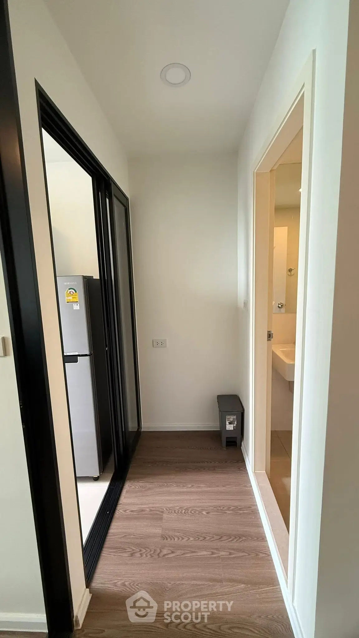 Modern apartment hallway with sleek flooring and access to kitchen and bathroom.