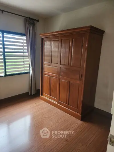 Spacious bedroom with wooden wardrobe and large window for natural light