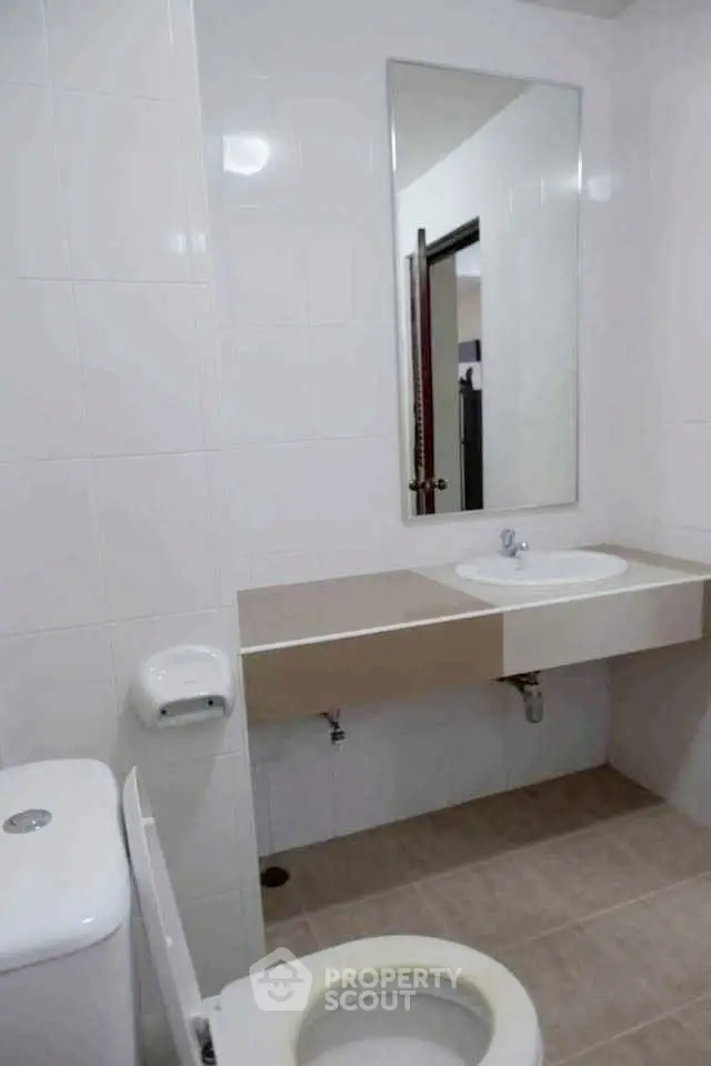 Modern bathroom with sleek design and neutral tones, featuring a large mirror and contemporary fixtures.