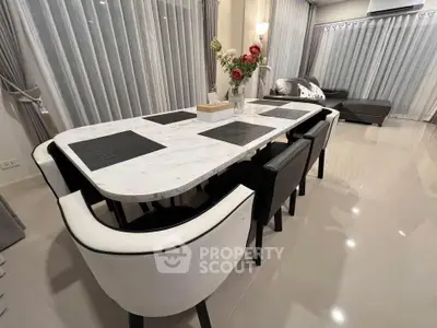 Elegant dining area with marble table and modern decor in a stylish living room setting.