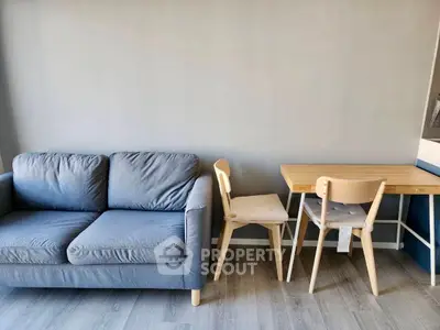 Modern living room with cozy blue sofa and wooden dining set on sleek flooring.
