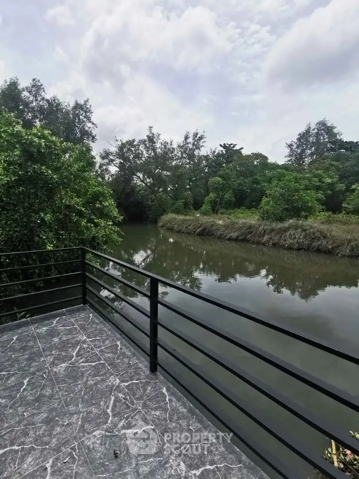 Stunning river view from a modern balcony with sleek railing and lush greenery.