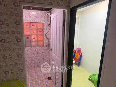Charming bathroom with floral tiles and adjacent playroom, perfect for family living.