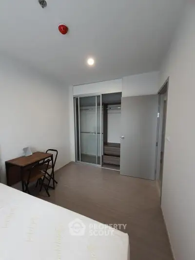 Modern bedroom with minimalist design, featuring a built-in wardrobe and a small study desk.