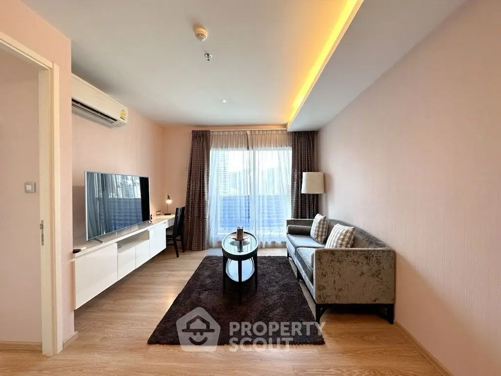 Modern living room with stylish furniture and natural light, featuring a cozy sofa and sleek TV setup.