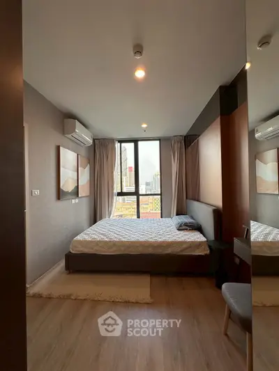 Modern bedroom with city view, featuring stylish decor and large window for natural light.