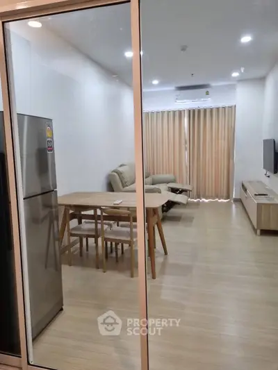 Spacious modern living room with gleaming hardwood floors, large windows draped in elegant curtains, and a full suite of contemporary furnishings including a sleek dining set and plush sofa.