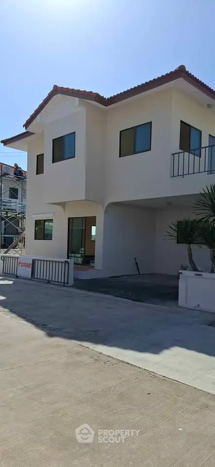 Modern two-story house with red-tiled roof and large windows, showcasing contemporary architecture and spacious design.