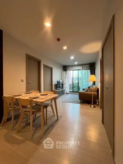 Modern apartment interior with dining and living area, featuring a cozy balcony view.