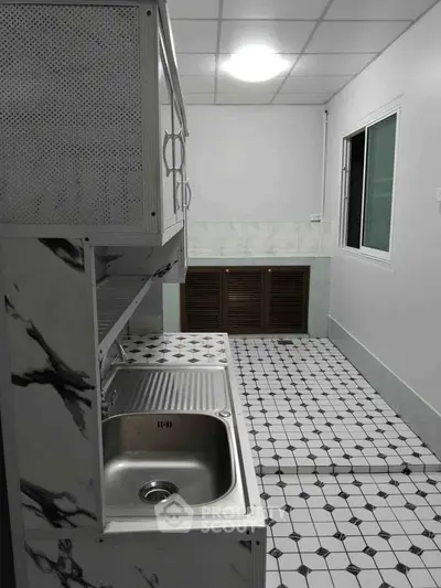 Modern kitchen with sleek marble countertops and stainless steel sink, featuring a closed layout and tiled flooring.