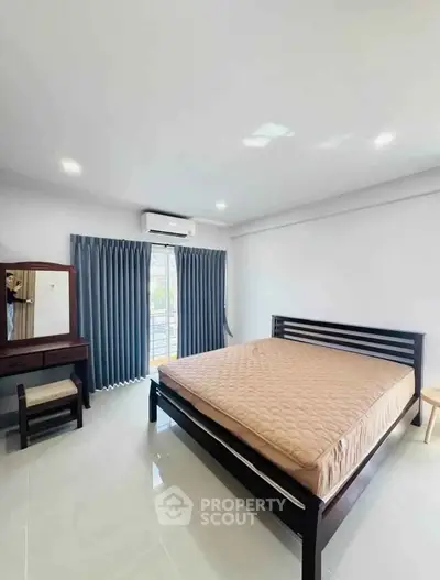 Spacious bedroom with modern furnishings and natural light, featuring a large bed and stylish decor.