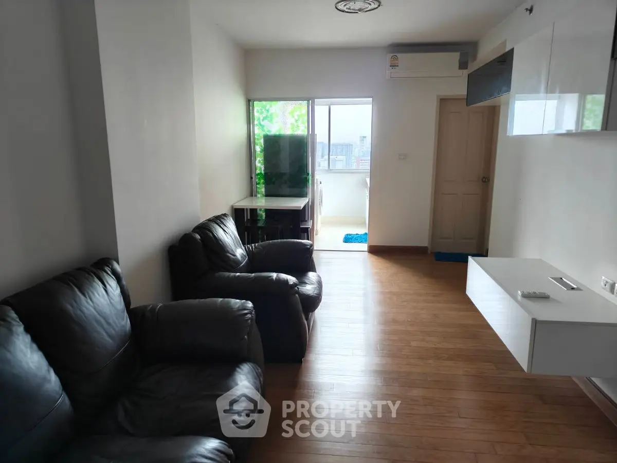 Spacious living room with leather sofas and balcony view in modern apartment.