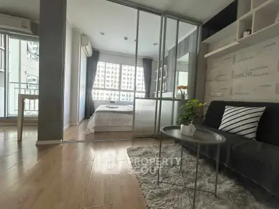 Modern apartment interior with glass partition, cozy living area, and bright bedroom view.